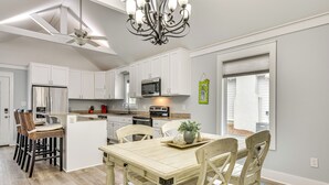Una cocina moderna con armarios blancos, una isla central y una zona de comedor con sillas de madera.
