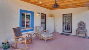 A covered patio area with wooden furniture, a rocking chair, a small table, and a refrigerator. - Peaceful & Historic Home in Patagonia! (Patagonia)