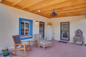 A covered patio area with wooden furniture, a rocking chair, a small table, and a refrigerator. - Peaceful & Historic Home in Patagonia! (Patagonia)