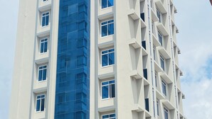 A tall building with a blue glass facade and white exterior walls. - Modern with City view, 12 minutes from the beach (Dar es Salaam)