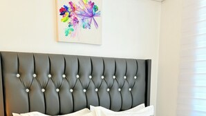 A neatly made bed with white linens, a tufted headboard, and decorative pillows. - Modern with City view, 12 minutes from the beach (Dar es Salaam)