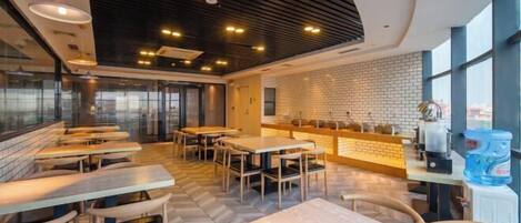 A modern cafe with wooden tables and chairs, a brick wall, and large windows.
