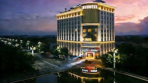 A multi-story hotel with a prominent 'BYHOTEL' sign, featuring a modern architectural design with a central atrium and a reflective pool in front. - Borrman Hotel Dongguan Zhongtang shop (Dongguan)
