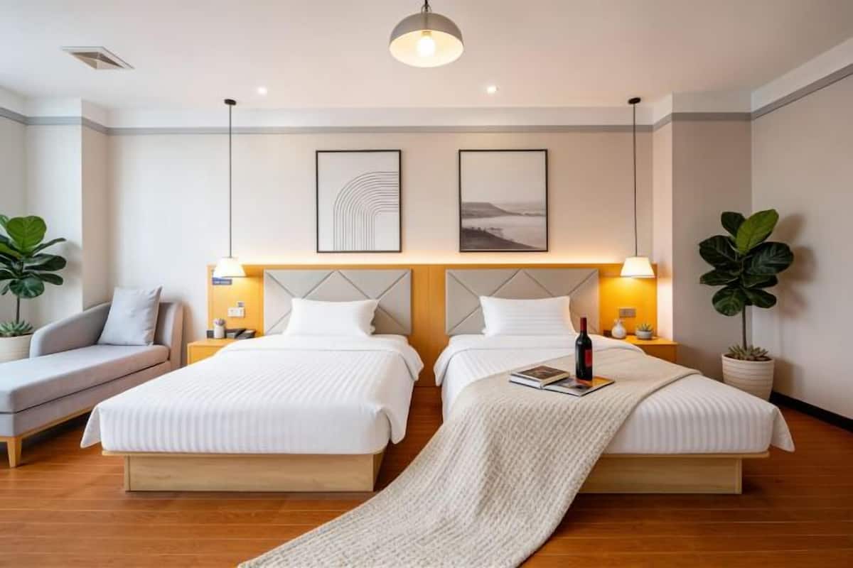 Quarto de hotel com duas camas, um sofá e uma janela grande.