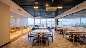 A modern restaurant with wooden flooring, brick walls, and large windows offering a city view. - Borrman Hotel Dongguan Zhongtang shop (Dongguan)