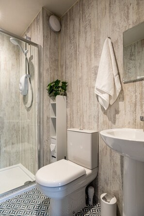 Un baño moderno con ducha, inodoro y lavamanos.