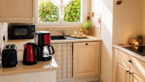 A kitchen with a window, a microwave, a kettle, a toaster, and a hanging light fixture. - House for 6 people with a quiet garden in Les Sables d'Olonne (Les Sables-d'Olonne)
