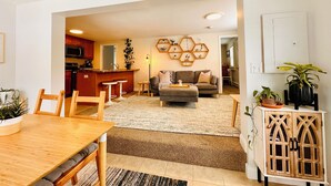 Ein modernes Wohnzimmer mit einer Couch, einem Couchtisch und einem Essbereich mit Holztisch und Stühlen.