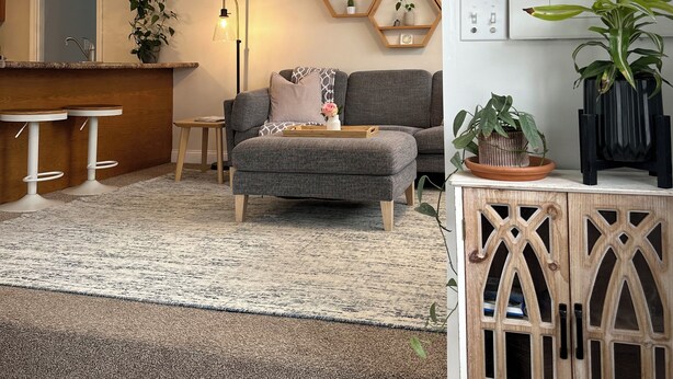 Ein modernes Wohnzimmer mit grauem Sofa, einer Holzkommode und sechseckigen Wandschränken.