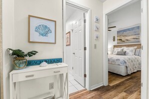 Une chambre à coucher avec un lit, une table de chevet et un mur orné d’une œuvre d’art sur le thème de la plage.