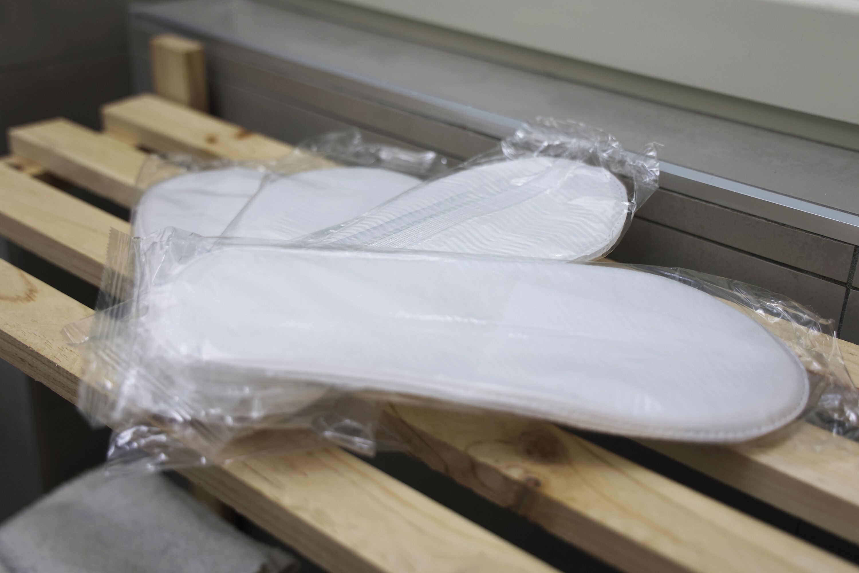 Zwei weiße, in Plastik verpackte Gegenstände auf einer Holztischplatte.