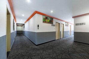 A hotel hallway with doors, a patterned carpet, and a wall with directional arrows. - Red House Hotel (Shanghai Red House Hospital Lujiabang Road Subway Station Branch) (Shanghai)