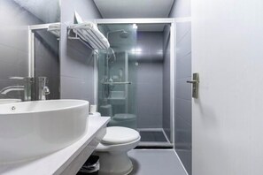 A modern bathroom with a large sink, toilet, and a glass-enclosed shower area. - Red House Hotel (Shanghai Red House Hospital Lujiabang Road Subway Station Branch) (Shanghai)