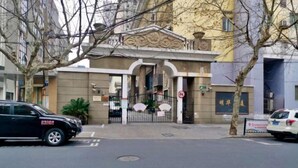 Ingresso di un edificio con viale recintato, divieto di parcheggio e cartello con caratteri cinesi.