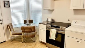 A compact kitchen with a dining table, chairs, a stove, and a washing machine. - Affordable + Pet Friendly 1 BR + sofa bed/1BA #B (Lubbock)