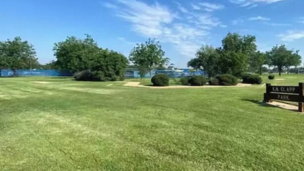 Naamplaatje voor E.J. Glapp Park, met een grasveld en bomen op de achtergrond.