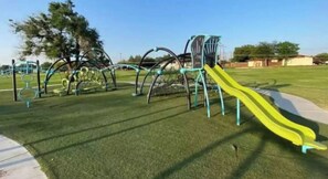Une aire de jeux avec un toboggan jaune et des structures d’escalade.