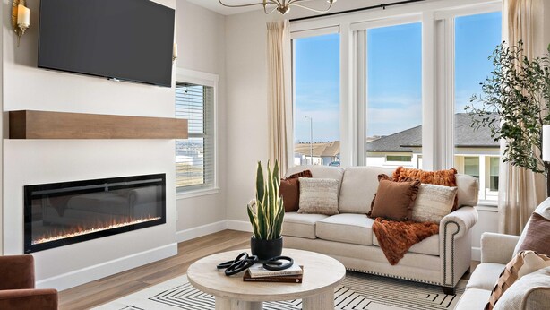 Ein modernes Wohnzimmer mit Kamin, Flachbildfernseher an der Wand, großem Fenster mit Stadtblick und einer Kronleuchter.