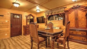 Un interior de madera con una mesa y sillas de comedor, un mueble de madera grande y una puerta.