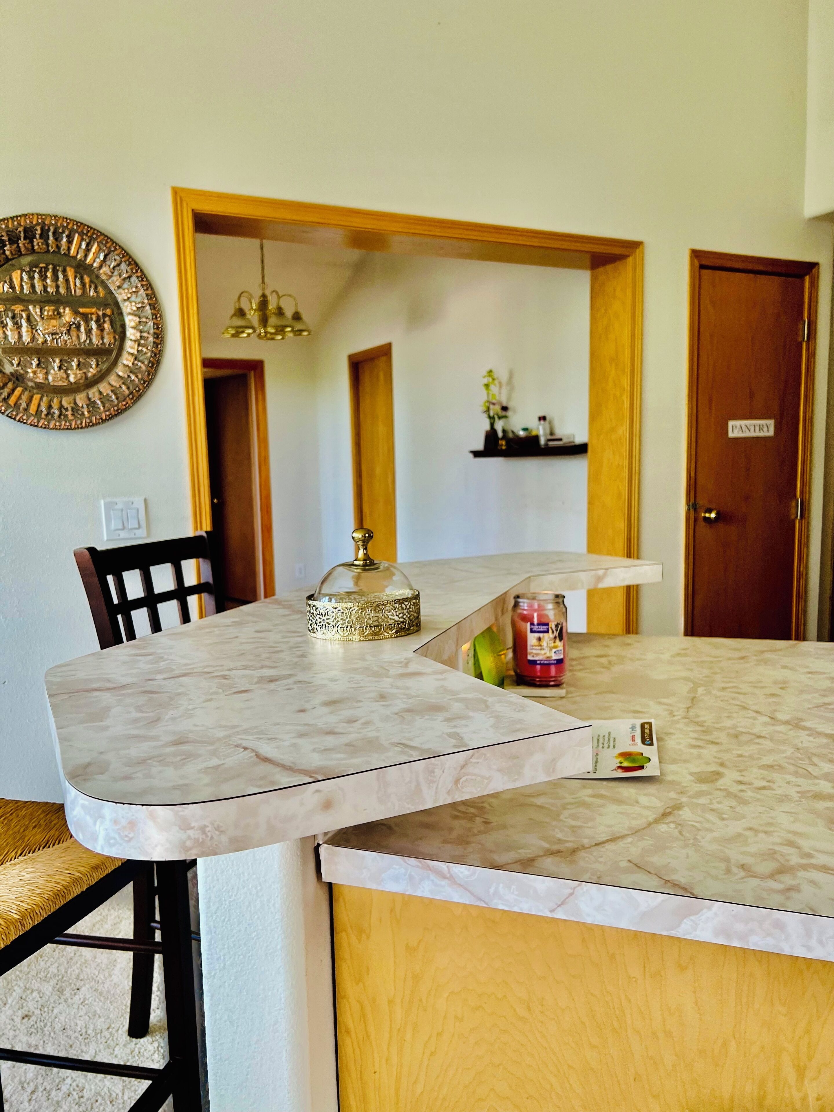 A dining area with a marble table, a chair, a decorative mirror, and a pantry door.