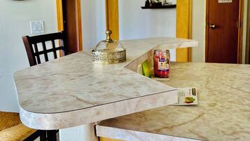 A dining area with a marble table, a chair, a decorative mirror, and a pantry door.