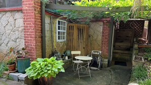 A small patio area with a table and chairs, surrounded by potted plants and a wooden fence. - Decatur Garden Studio Apartment (Decatur)