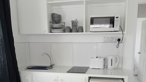 A compact kitchen with white cabinets, a microwave, a toaster, and a small refrigerator. - Charming One-Bedroom Apartment in Peaceful Telescope, St. Andrews, Grenada (Telescope)