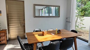 A dining area with a wooden table and black chairs, a mirror on the wall, and a door to the left. - Beautiful house for rent, walking distance to the beach 1 bedroom plus sofabed (Playa del Carmen)