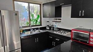 A modern kitchen with black cabinets, a stainless steel refrigerator, a gas stove, and a red toaster. - Beautiful house for rent, walking distance to the beach 1 bedroom plus sofabed (Playa del Carmen)