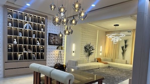 A modern living room with a glass coffee table, a sofa, and a dining area with a bench.