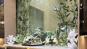 A reception desk with a large mirror, decorative plants, and a chessboard.