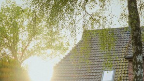 A rustic house with a tiled roof, a window, and a small garden area with a table and chairs. - House by the lake with plenty of space, right next to the Lüneburg Heath parks (Rethem)