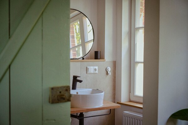 A bathroom with a white sink, a mirror above it, and a window to the right. - House by the lake with plenty of space, right next to the Lüneburg Heath parks (Rethem)