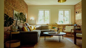 A cozy living room with a brick wall, a sofa, a coffee table, and a bookshelf. - House by the lake with plenty of space, right next to the Lüneburg Heath parks (Rethem)