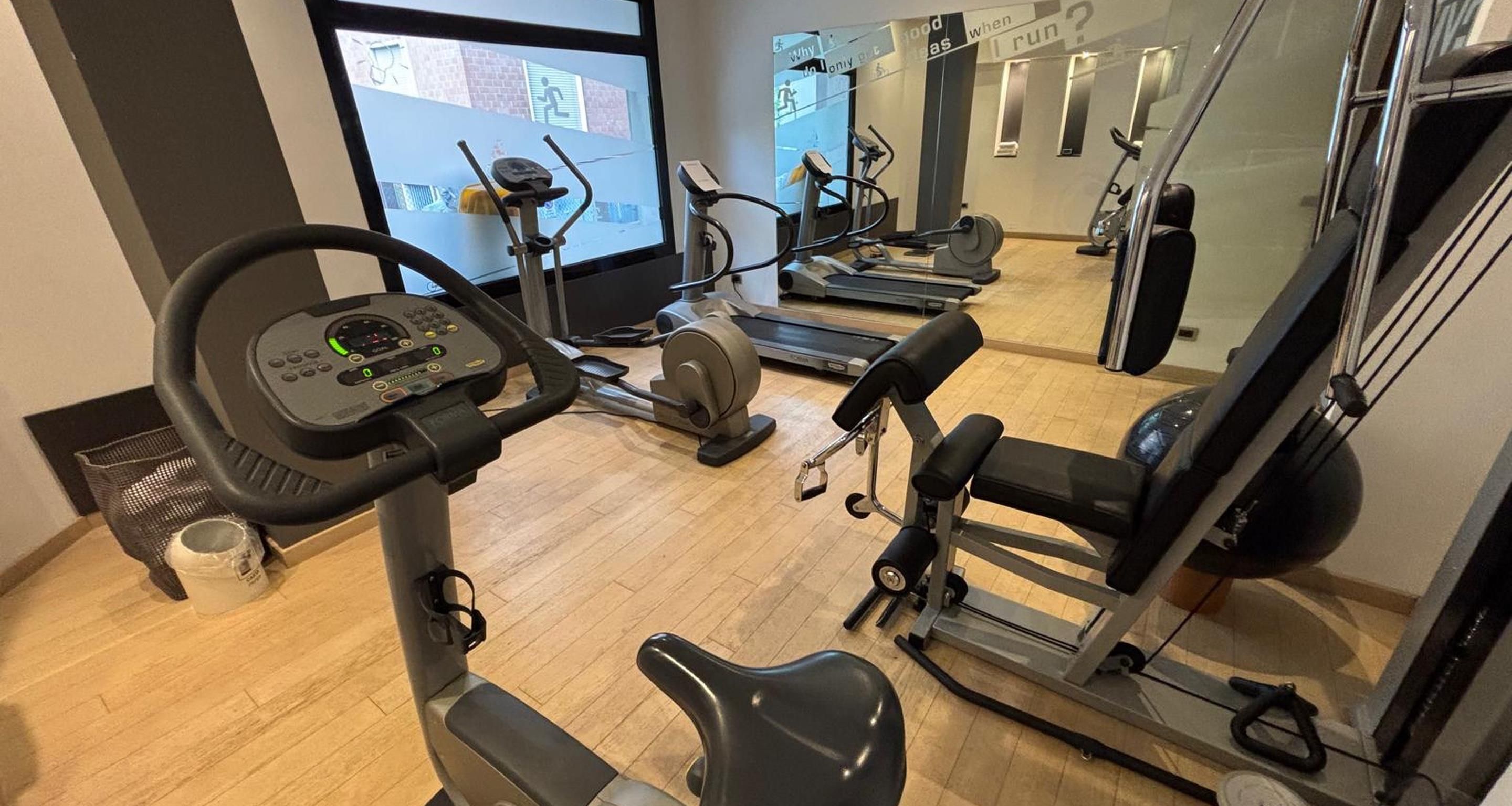 Un gimnasio con equipo cardiovascular, incluyendo cintas de correr y una máquina elíptica.
