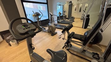 Un gimnasio con equipo cardiovascular, incluyendo cintas de correr y una máquina elíptica.