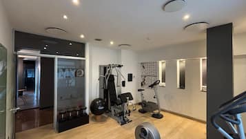 A modern gym with various exercise equipment, including a treadmill, weight machines, and a wall-mounted mirror.