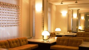 A hotel lobby with a seating area, a lamp, and a mirror.