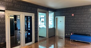 A hotel lobby with a polished floor, a blue bench, and a door leading to a room. - Sure Hotel By Best Western Milano (Padova)