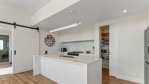 Cozinha moderna com ilha central, armários brancos e piso de madeira.