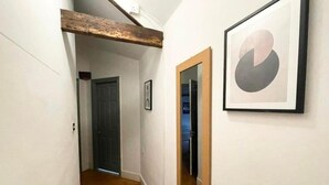 A narrow hallway with wooden flooring, a wooden ceiling beam, and a door at the end. - City Centre 2bed Apartment Wi-fi Parking (Newcastle-upon-Tyne)
