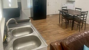 Eine kompakte Küche mit Kühlschrank, Spüle und Essbereich mit Tisch und Stühlen.