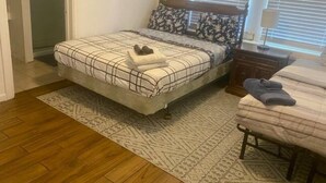 Ein Schlafzimmer mit einem Bett, einem Nachttisch, einer Kommode und einem Fenster mit Jalousien.