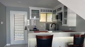 A modern kitchen with white cabinetry, a stainless steel sink, and two bar stools.