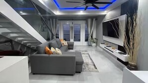 A modern living room with a grey sectional sofa, a flat-screen TV, and a ceiling fan.