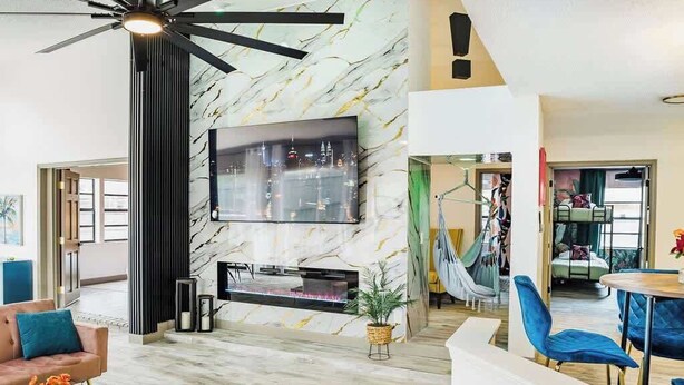 Una sala de estar moderna con un televisor grande, una chimenea y un ventilador de techo.