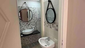 Un baño con un lavamanos blanco, un espejo y un bidé.