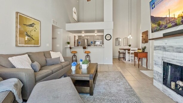 A spacious living room with a high ceiling, a fireplace, and a dining area. - Perfect Chandler Getaway – Cozy Condo in the Heart of the East Valley! (Chandler)
