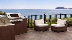 An outdoor patio with a grill, two wicker chairs, and a view of the sea. - A Caribbean Escape with Unforgettable Views - Marriott's Frenchman's Cove - 2 Bd (Southside)
