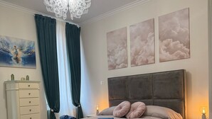 Ein Schlafzimmer mit einem großen Bett, einer Chandelier, einem Schminktisch und einem Gemälde an der Wand.
